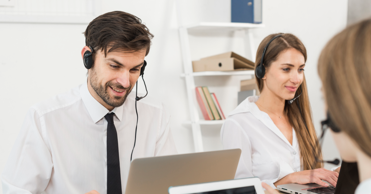 An image of a man and woman in a call center, both wearing headsets, symbolizing the transformation of contact center experiences through AI in customer service