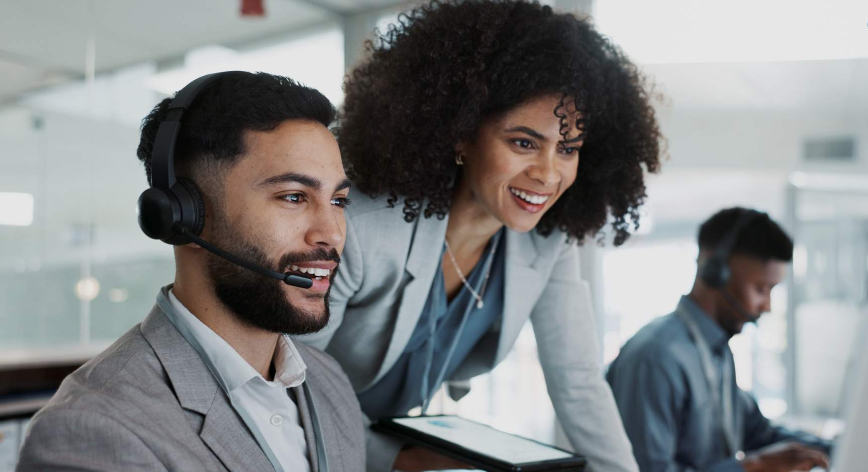 Real-Time Agent Assist Image showing two employees looking at a computer monitor to show emphasis on Real-Time Agent Assist