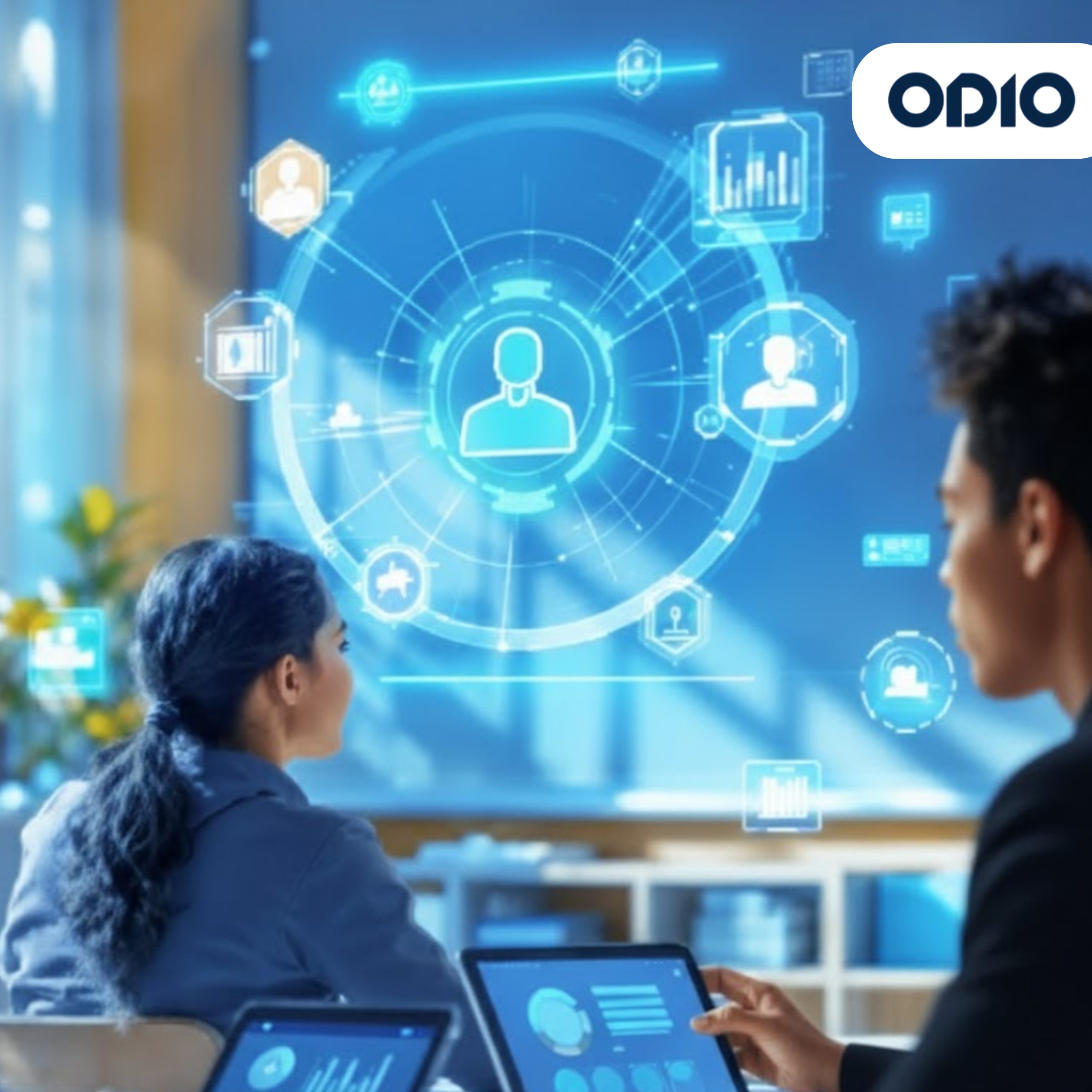 Connecting the Data: User Intelligence A dynamic image of three people at a desk using tablets. A man on the right and a woman in the center are focused on their screens, which display data graphs. A large, bright blue holographic interface with various icons for users, charts, and data analysis is projected over the scene.